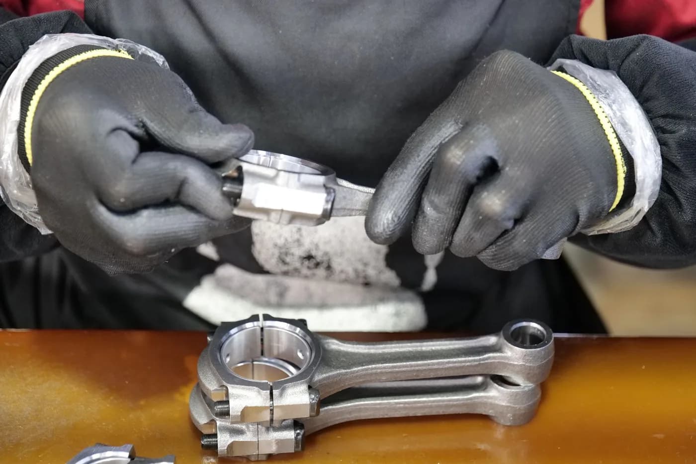 A technician assembling an engine connecting rod on an automotive line