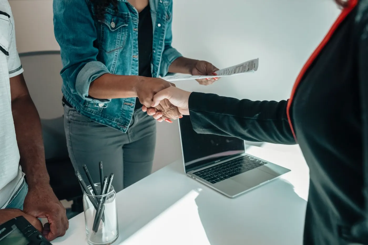 Two people shaking hands across a desk